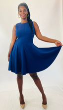 Load image into Gallery viewer, Additional full-body front view of a size 16 Michael Kors navy blue high-neck a-line dress with circle skirt styled with tan patent leather pumps on a size 12 model.
