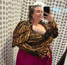 Load image into Gallery viewer, Front view focusing on the very puffed and dramatic sleeve of a size 3X Rebdolls brown, black, and white leopard pattern wrap top with puff sleeves styled with a magenta maxi skirt on a size 24 model.
