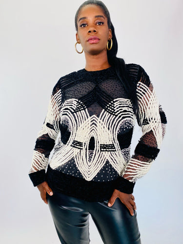 Front view of a size XL Naeem Khan black and white velvet, mesh, and beaded long sleeve blouse styled with black pleather pants on a size 12 model.