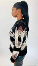Load image into Gallery viewer, Side view of a size XL Naeem Khan black and white velvet, mesh, and beaded long sleeve blouse styled with black pleather pants on a size 12 model.
