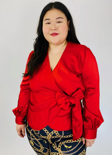 Front view of this stunning size 14, size 16 Jonathan Simkhai vibrant red draped wrap top with bow detail styled with faux Versace chain patterned leggings on size 14/16 model.