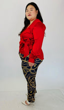 Load image into Gallery viewer, Full-body side view of this stunning size 14, size 16 Jonathan Simkhai vibrant red draped wrap top with bow detail styled with faux Versace chain patterned leggings and white strappy heels on size 14/16 model.
