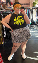Load image into Gallery viewer, Full-body front view of a size 3X Forever 21 black and white ditsy floral mini circle skirt styled with a black tank and white crocs on a size 22/24 model.
