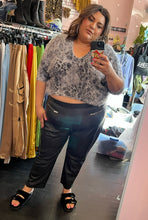 Load image into Gallery viewer, Final full-body front view of a pair of size 26 Ellos black genuine leather tapered pants with zipper pockets styled with a gray fuzzy cropped sweater and black slides on a size 18/20 model.
