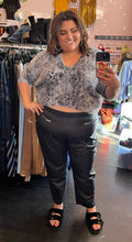 Load image into Gallery viewer, Additional full-body front view of a pair of size 26 Ellos black genuine leather tapered pants with zipper pockets styled with a gray fuzzy cropped sweater and black slides on a size 18/20 model.

