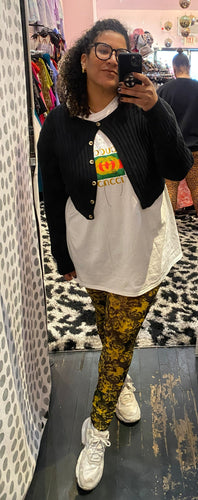 Full-body front view of a pair of GANNI black and yellow floral mesh leggings styled with an oversized white tee and cropped black cardigan on a size 16/18 model.