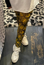 Load image into Gallery viewer, Close up front view of a pair of GANNI black and yellow floral mesh leggings styled with an oversized white tee on a size 16/18 model.
