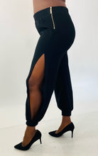 Load image into Gallery viewer, Additional side view of a pair of size 14 Haney for 11Honoré black slit calf joggers styled with black pumps on a size 12 model.

