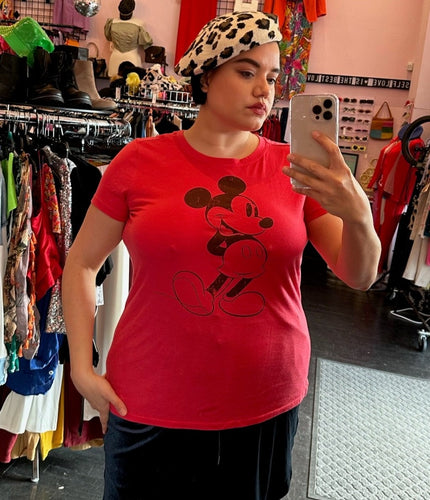 Front view of a size 0 Disney red Mickey Mouse cartoon graphic t-shirt with vintage-inspired distressing styled with a navy blue velvet mini skirt and a leopard beret on a size 14/16 model.
