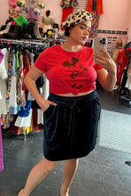 Load image into Gallery viewer, Front view of a size 0 Disney red Mickey Mouse cartoon graphic t-shirt with vintage-inspired distressing styled tied in a knot over a navy blue velvet mini skirt and a leopard beret on a size 14/16 model.

