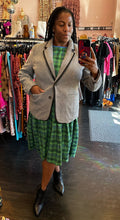 Load image into Gallery viewer, Full-body front view of a size XXL Rudie vibrant green plaid babydoll style midi dress styled under a gray blazer with black boots on a size 16 model.
