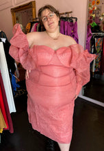 Load image into Gallery viewer, Additional front view of a size 24 ASOS peachy pink lace sheath dress with a corset-style bodice and oversized ruffle bust and sleeves with puff sleeves on a size 24 model. The photo is taken inside in front of a window, for a combination of natural and overhead lighting.
