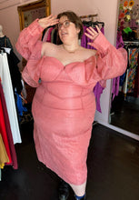 Load image into Gallery viewer, Additional front view showing off the sleeves of a size 24 ASOS peachy pink lace sheath dress with a corset-style bodice and oversized ruffle bust and sleeves with puff sleeves on a size 24 model. The photo is taken inside in front of a window, for a combination of natural and overhead lighting.
