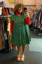 Load image into Gallery viewer, Additional full-body front view of a size XXL Rudie vibrant green plaid babydoll style midi dress styled over a red turtleneck with red and white sneakers on a size 16/18 model.
