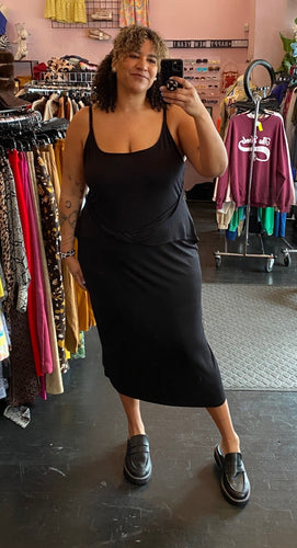 Full-body front view of a size 24 ASOS black tank maxi dress with twisted waist detail styled with black loafers on a size 16/18 model.