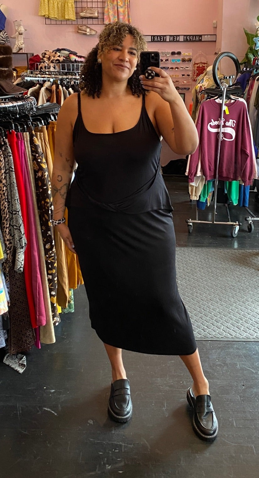 Full-body front view of a size 24 ASOS black tank maxi dress with twisted waist detail styled with black loafers on a size 16/18 model.