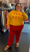 Load image into Gallery viewer, Full-body front view of a pair of size 24W Anne Klein red trousers styled with a yellow and red graphic tee and brown slides on a size 24 model.
