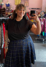 Load image into Gallery viewer, Front view of a size 4 Torrid black blouse with lace scallop-edge sleeves and darted neckline styled tucked into a blue and black plaid skirt on a size 16/18 model.
