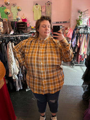 Close up front view of a size 3X Walk of Shame brand yellow, red, and white snap-button closure blouse with drawstring neckline and asymmetrical side details on a size 24 model.