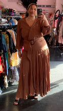 Load image into Gallery viewer, Additional full-body front view of a size 1 Fashion to Figure brown tiered maxi wrap dress with a tortoiseshell belt buckle styled with black heels on a size 16/18 model.
