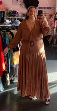 Load image into Gallery viewer, Full-body front view of a size 1 Fashion to Figure brown tiered maxi wrap dress with a tortoiseshell belt buckle styled with black heels on a size 16/18 model.
