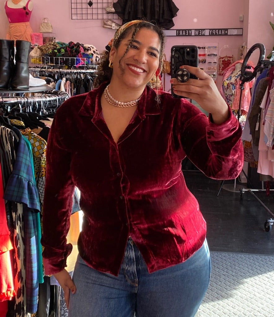 Front view of a size 18 JC Obando for 11 Honoré deep red crushed velvet collared button-up blouse styled with medium-lightwash denim on a size 16/18 model.