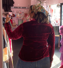 Load image into Gallery viewer, Back view of a size 18 JC Obando for 11 Honoré deep red crushed velvet collared button-up blouse styled with medium-lightwash denim on a size 16/18 model.
