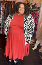 Load image into Gallery viewer, Full-body front view of a size 26/28 Eloquii muted red-orange sleeveless maxi dress styled under a fuzzy zebra striped cardigan with black mules on a size 24/26 model.
