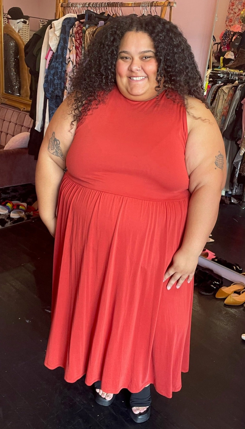Full-body front view of a size 26/28 Eloquii muted red-orange sleeveless maxi dress styled with black mules on a size 24/26 model.