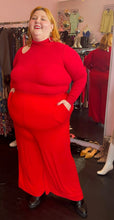 Load image into Gallery viewer, Full-body front view of a size XXXL Zelie for She bright red wide leg stretchy palazzo pant styled with a red turtleneck and black boots on a size 22/24 model.
