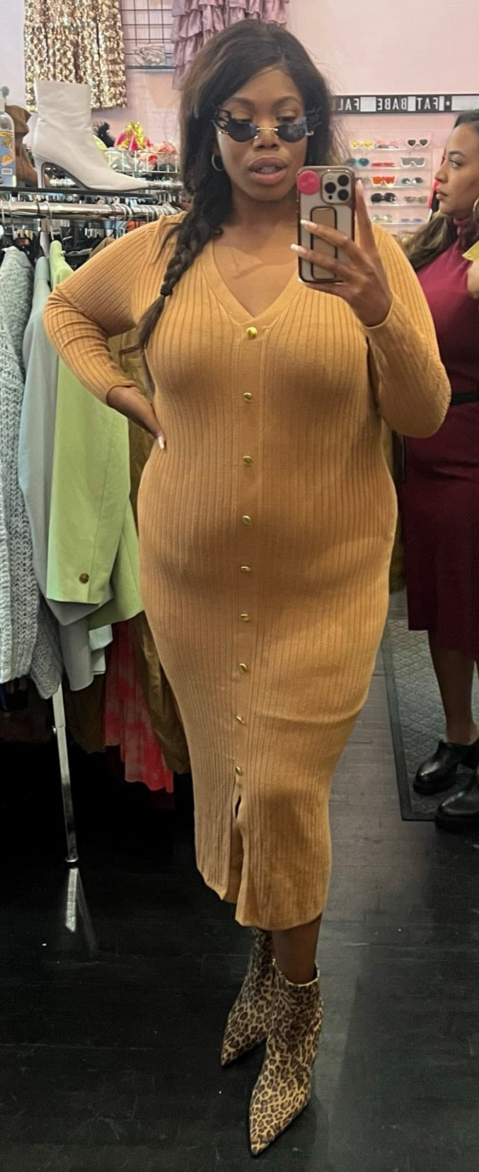 Full-body front view of a size XL Jeannie Mai x INC tan ribbed v-neck sweater dress with gold faux buttons and a small front slit styled with leopard boots on a size 14/16 model.