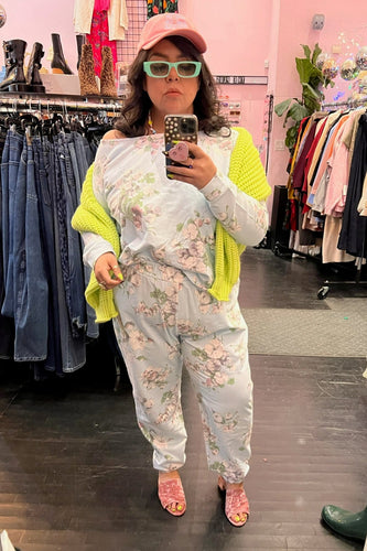 Full-body front view of a size 16 ASOS baby blue and white floral 2-piece lounge set styled with a chartreuse sweater, pink cap, and teal sunglasses on a size 14/16 model.