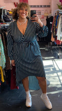 Load image into Gallery viewer, Additional full-body front view of a size 3X Black Ivy brand dark teal and white vertical striped faux wrap midi dress with high-low hemline styled with white sneakers on a size 16/18 model.

