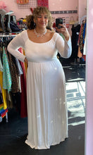 Load image into Gallery viewer, Full-body front view of a size 3X Pink Blush brand off-white floor length maxi dress with scoop neck styled with pearl necklaces on a size 16/18 model. The photo is taken inside in overhead lighting.
