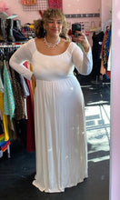 Load image into Gallery viewer, Full-body front view of a size 3X Pink Blush brand off-white floor length maxi dress with scoop neck styled with pearl necklaces on a size 16/18 model. The photo is taken inside in overhead lighting.
