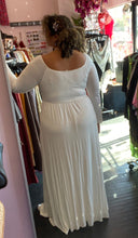 Load image into Gallery viewer, Full-body back view of a size 3X Pink Blush brand off-white floor length maxi dress with scoop neck styled with pearl necklaces on a size 16/18 model. The photo is taken inside in overhead lighting.
