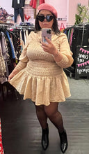 Load image into Gallery viewer, Full-body front view of a size L H&amp;M light cream smocked torso mini dress with puff sleeves and a high neckline styled with black tights and black hoots on a size 14/16 model.
