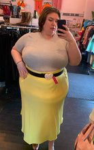 Load image into Gallery viewer, Full-body front view of a size M Universal Standard light gray ribbed tee shirt styled tucked into a yellow midi skirt with a black heart belt on a size 24 model.
