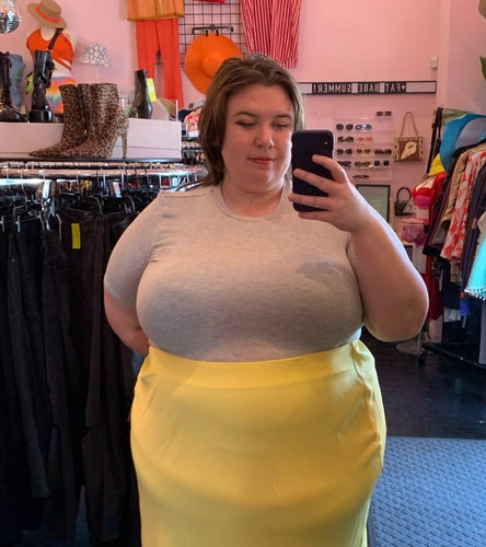 Front view of a size M Universal Standard light gray ribbed tee styled tucked into a yellow midi skirt on a size 24 model.