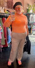Load image into Gallery viewer, Full-body front view of a pair of size XXL H&amp;M off-white and black diagonally striped silky drawstring pants styled with an orange sheer mesh mockneck top, a black beret, and pink slides on a size 16/18 model.
