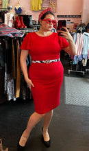 Load image into Gallery viewer, Additional full-body front view of a size 14 Calvin Klein red flutter sleeve sheath midi dress styled with black pumps, a cow-print belt, and red accessories on a size 14/16 model.
