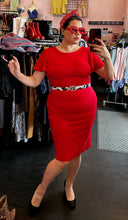 Load image into Gallery viewer, Full-body front view of a size 14 Calvin Klein red flutter sleeve sheath midi dress styled with black pumps, a cow-print belt, and red accessories on a size 14/16 model.
