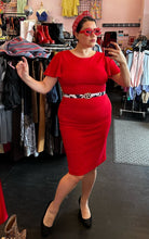 Load image into Gallery viewer, Final full-body front view of a size 14 Calvin Klein red flutter sleeve sheath midi dress styled with black pumps, a cow-print belt, and red accessories on a size 14/16 model.
