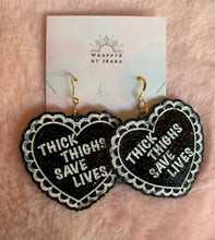 Load image into Gallery viewer, Another close up on the black lacquer valentine heart earrings that read &quot;Thick Thighs Save Lives&quot; with chunky glitter inside!
