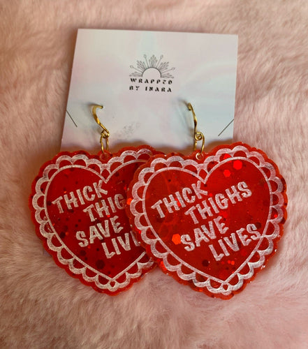 Close up on the red transluscent valentine heart earrings that read 