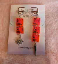 Load image into Gallery viewer, Close up of the pink &amp; silver colorway of these Wrapped By Inara &quot;FAT ICON&quot; elemental earrings with a little sun charm and a needle charm on either earring.
