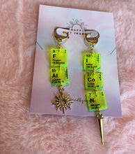 Load image into Gallery viewer, Additional close up of the green &amp; gold colorway of these Wrapped By Inara &quot;FAT ICON&quot; elemental earrings with a little sun charm and a needle charm on either earring.
