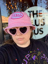 Load image into Gallery viewer, Side-long close up on the pink FAT BITCH bucket hat, a black hat with a white and pink embroidered patch that reads &quot;Fat Bitch.&quot;
