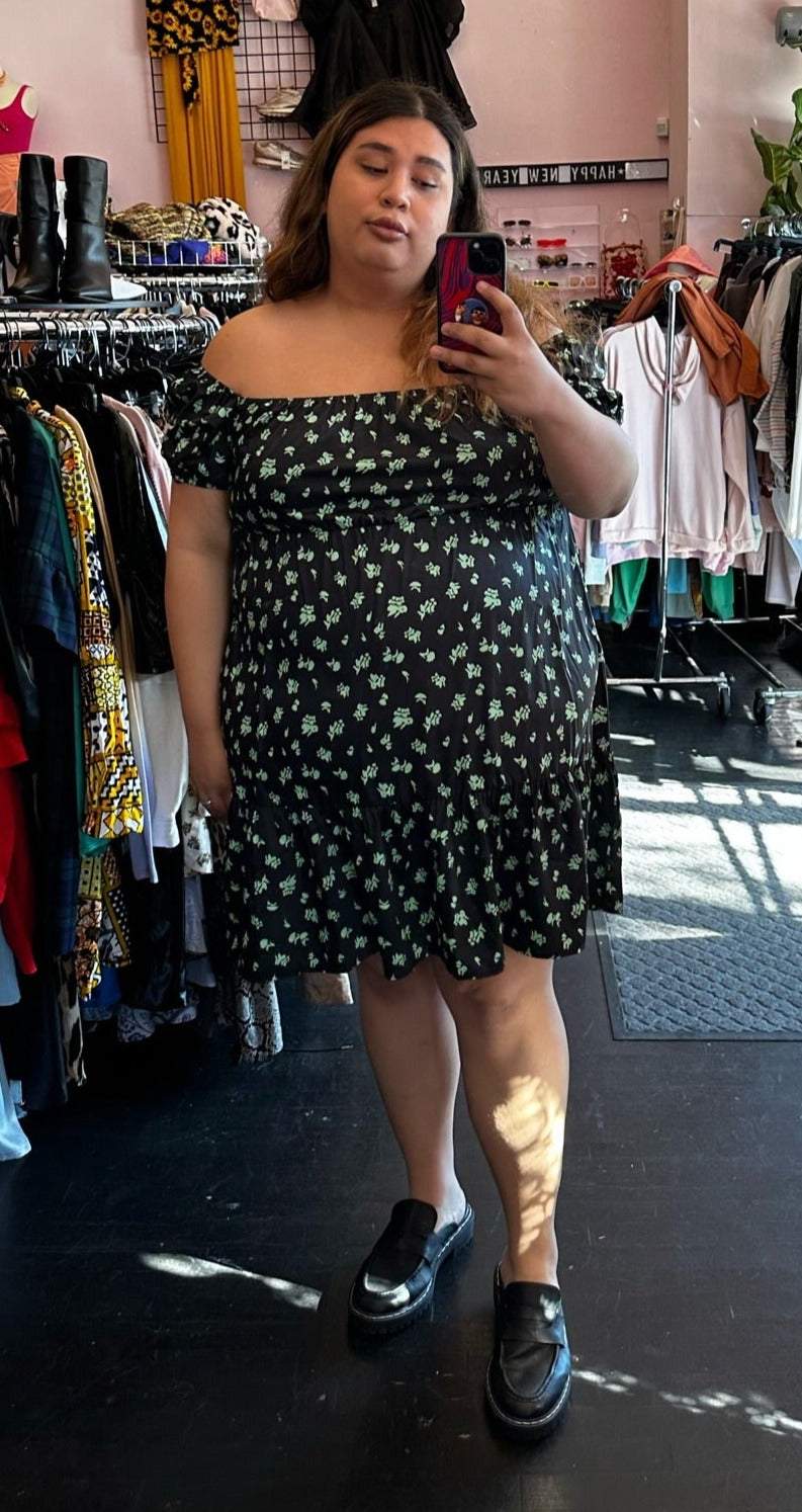 Full-body front view of a size 24 Nasty Gal black and neon green floral pattern puff sleeve mini dress styled with black loafers on a size 22 model.
