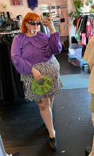Load image into Gallery viewer, Additional full-body front view of a size 28 Eloquii vibrant purple draped and gathered blouse with balloon sleeves styled with a zebra ruffled skirt and a green handband on a size 22/24 model.
